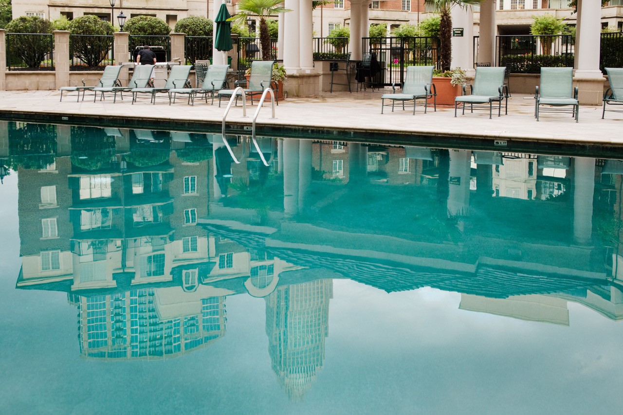 A pool with chairs and umbrellas in the background.